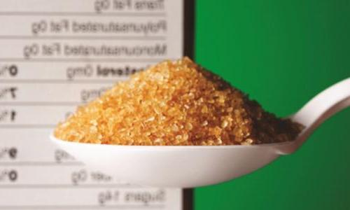 A spoon of raw sugar hovers in front of a cereal box's nutrition facts